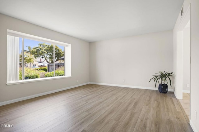 unfurnished room with baseboards, light wood-style flooring, and visible vents