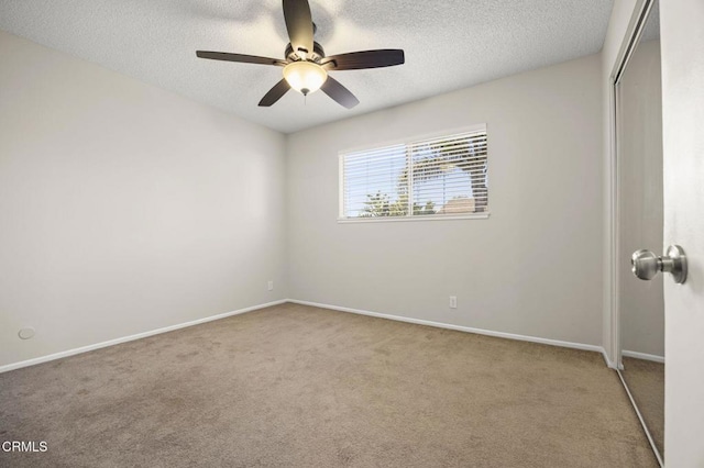 spare room with carpet floors, a ceiling fan, a textured ceiling, and baseboards