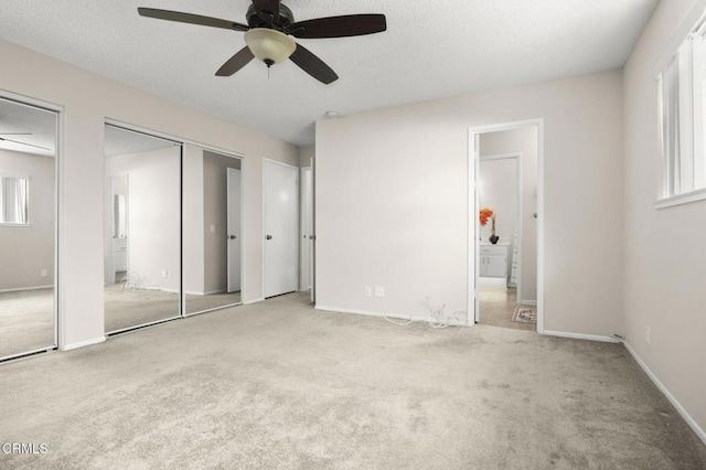 unfurnished bedroom featuring multiple closets, ensuite bathroom, baseboards, ceiling fan, and carpet