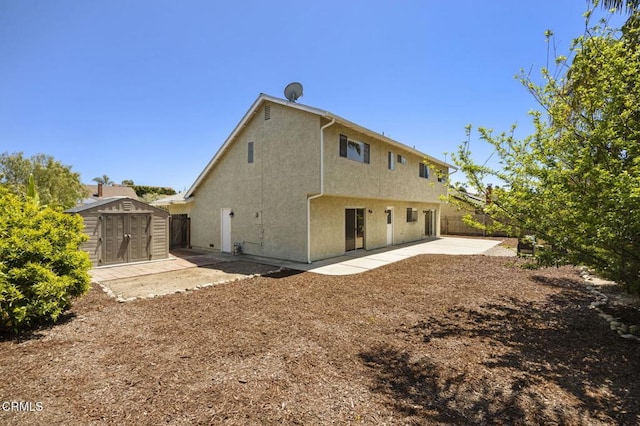 back of property featuring an outdoor structure, fence, stucco siding, a shed, and a patio area