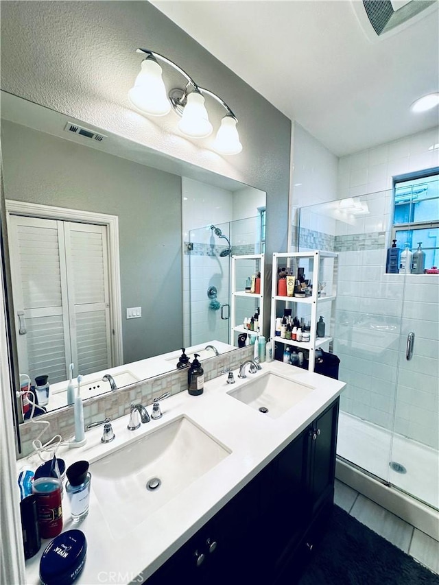 bathroom with visible vents, a sink, and a stall shower