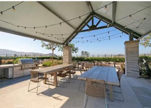 view of patio / terrace with grilling area, outdoor dining space, an outdoor kitchen, and a mountain view
