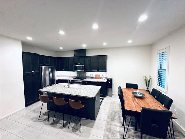 kitchen with appliances with stainless steel finishes, a sink, a kitchen island with sink, and recessed lighting