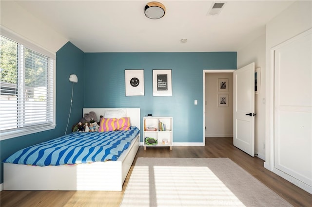 bedroom with baseboards, wood finished floors, and visible vents