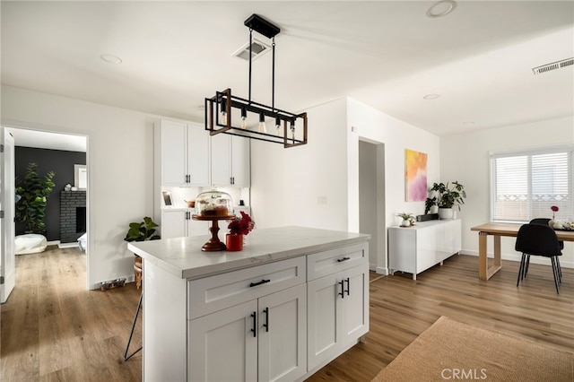 kitchen featuring white cabinets, baseboards, wood finished floors, and visible vents