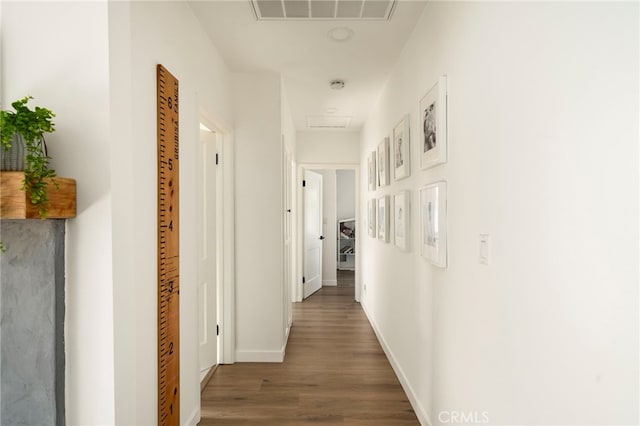 hall with attic access, baseboards, wood finished floors, and visible vents