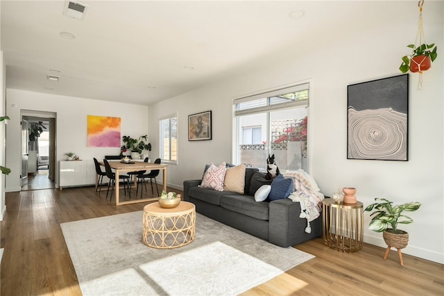 living area with baseboards, wood finished floors, and visible vents