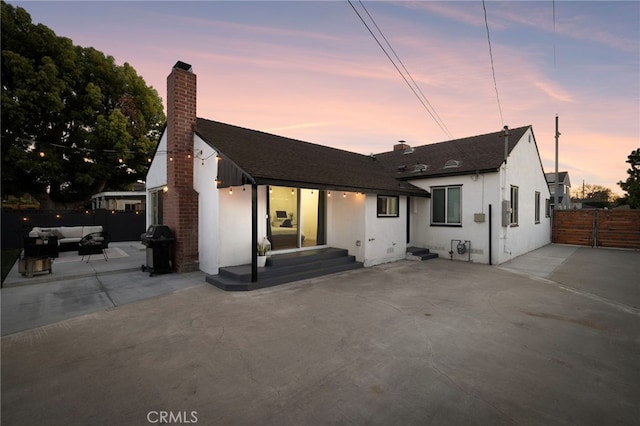 view of front of house with a chimney, a shingled roof, fence, a patio, and an outdoor hangout area