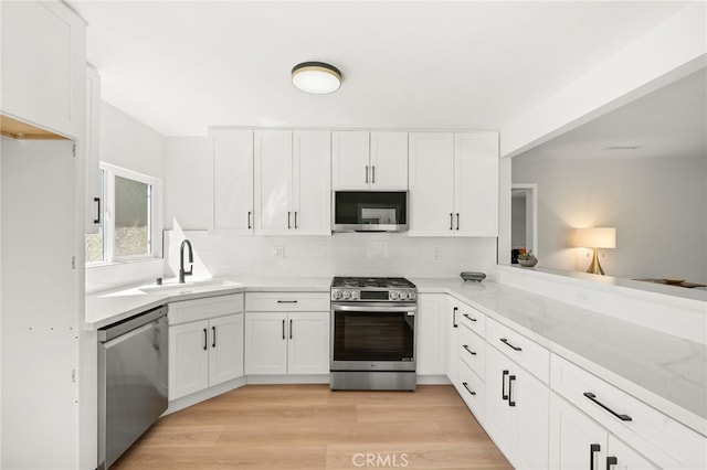 kitchen with white cabinets, stainless steel appliances, a sink, and backsplash