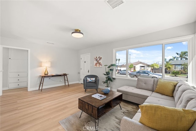 living area with light wood-style floors, visible vents, and baseboards