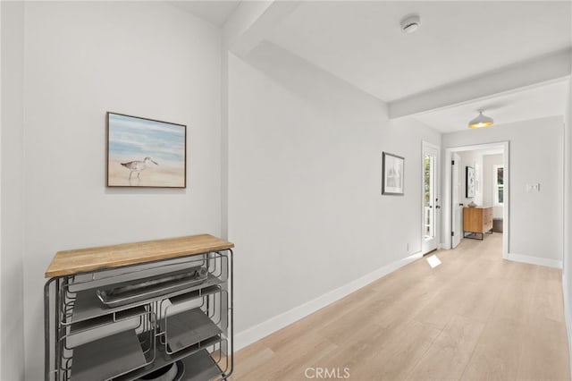 corridor with baseboards and light wood-style flooring