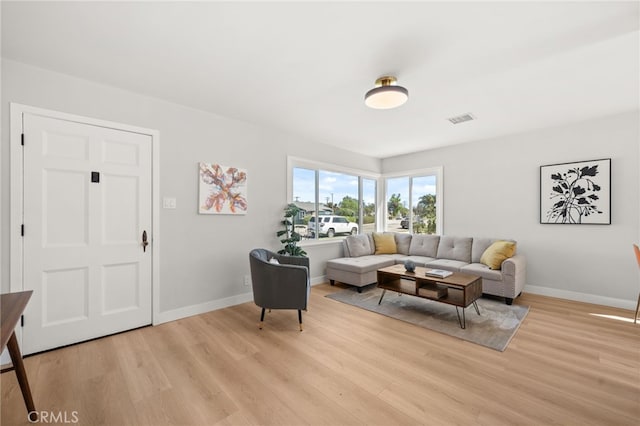 living room with baseboards, light wood-style floors, and visible vents