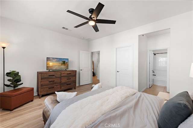 bedroom featuring ensuite bath, a ceiling fan, visible vents, and light wood-style floors