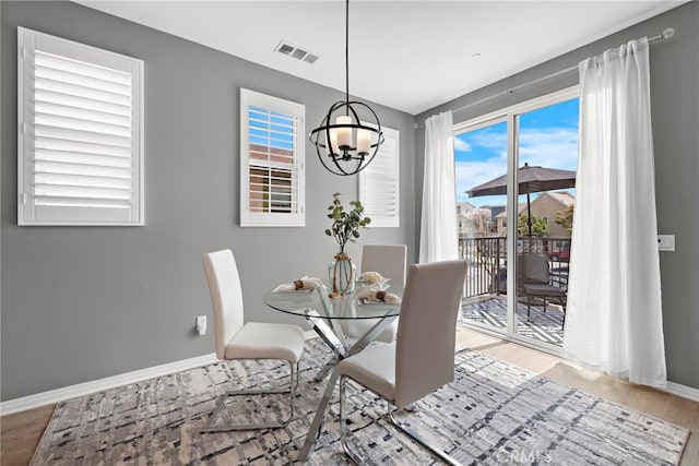 dining room with baseboards, a notable chandelier, wood finished floors, and visible vents