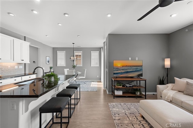 living area with baseboards, a ceiling fan, light wood finished floors, and recessed lighting