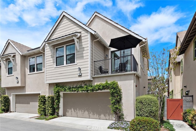 multi unit property featuring an attached garage, a balcony, and stucco siding