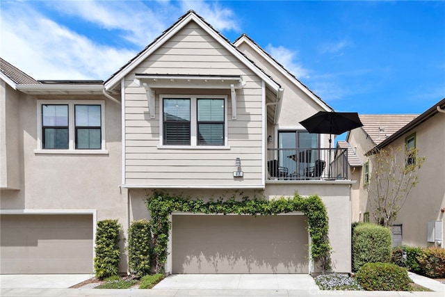 view of front of property with concrete driveway, stucco siding, a balcony, and a garage