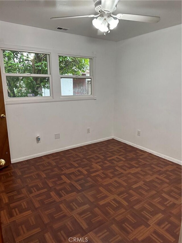 spare room featuring a ceiling fan, visible vents, and baseboards