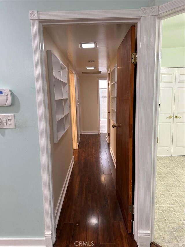 corridor with baseboards and dark wood-style flooring