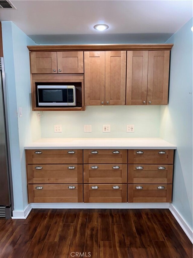 kitchen with baseboards, appliances with stainless steel finishes, and dark wood-type flooring