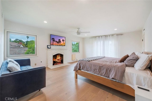 bedroom featuring a brick fireplace, recessed lighting, ceiling fan, and light wood-type flooring