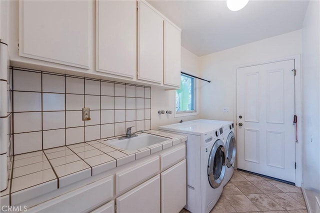 laundry area featuring a sink, cabinet space, light tile patterned flooring, and washer and dryer