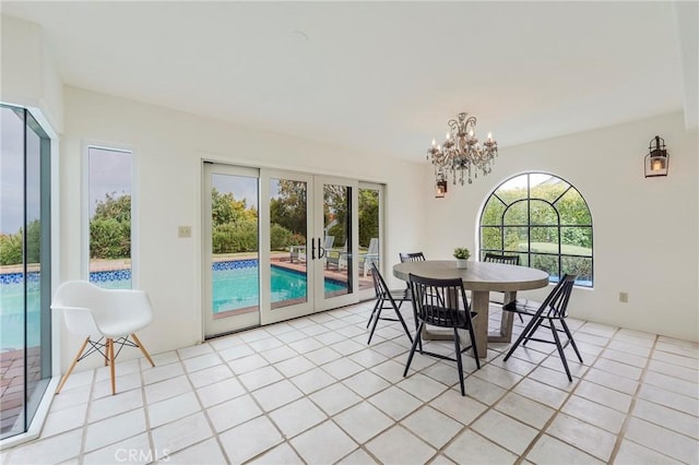 dining area with light tile patterned flooring, a notable chandelier, plenty of natural light, and french doors