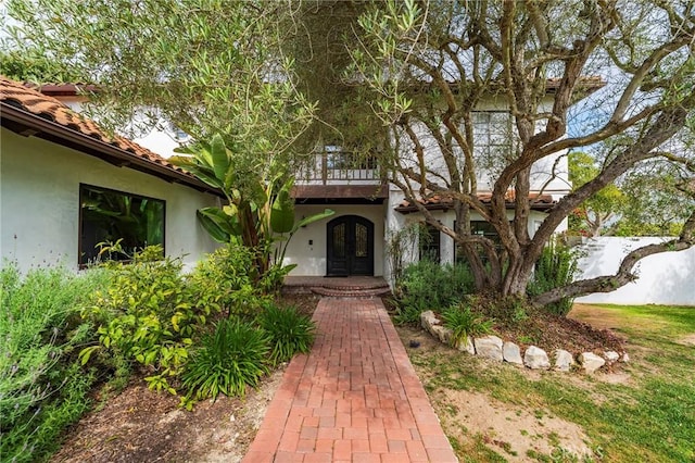 view of exterior entry featuring a tiled roof, stucco siding, and french doors