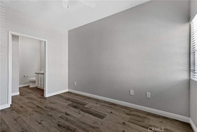 unfurnished bedroom featuring baseboards, a ceiling fan, wood finished floors, and connected bathroom