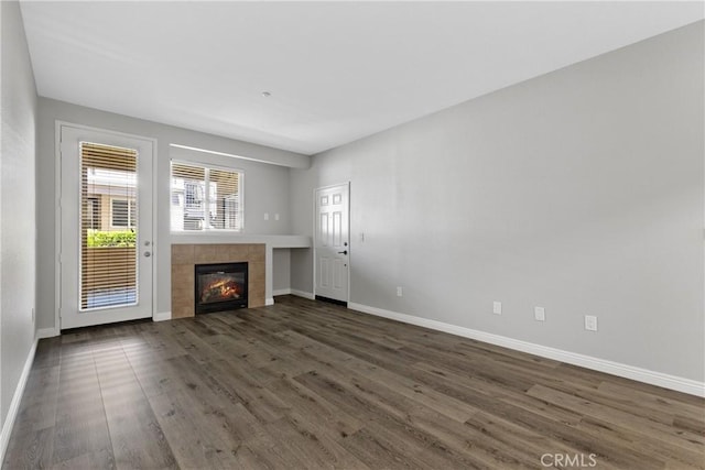 unfurnished living room with dark wood-type flooring, baseboards, and a fireplace