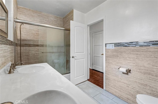 bathroom with tile patterned floors, vanity, tile walls, toilet, and an enclosed shower