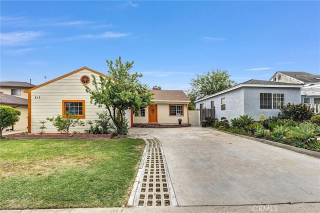 single story home featuring concrete driveway, fence, a chimney, and a front yard
