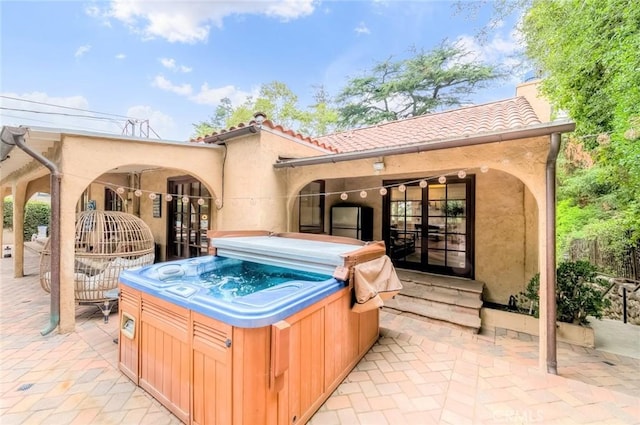 exterior space with a patio, a hot tub, and stucco siding