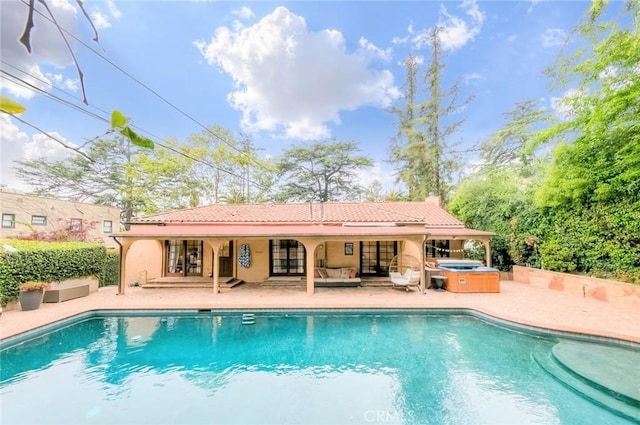 outdoor pool with a hot tub, a patio, and an outdoor living space