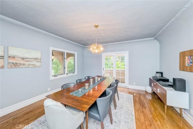 dining room with light wood-style floors, baseboards, ornamental molding, and a notable chandelier
