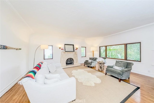 living room featuring light wood-style floors, baseboards, ornamental molding, and a fireplace