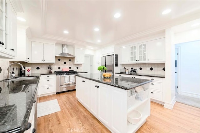 kitchen featuring open shelves, wall chimney exhaust hood, a sink, light wood-style flooring, and stainless steel appliances