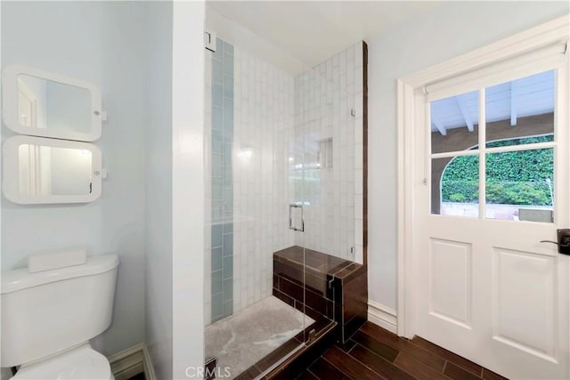 bathroom featuring baseboards, a stall shower, toilet, and wood finished floors