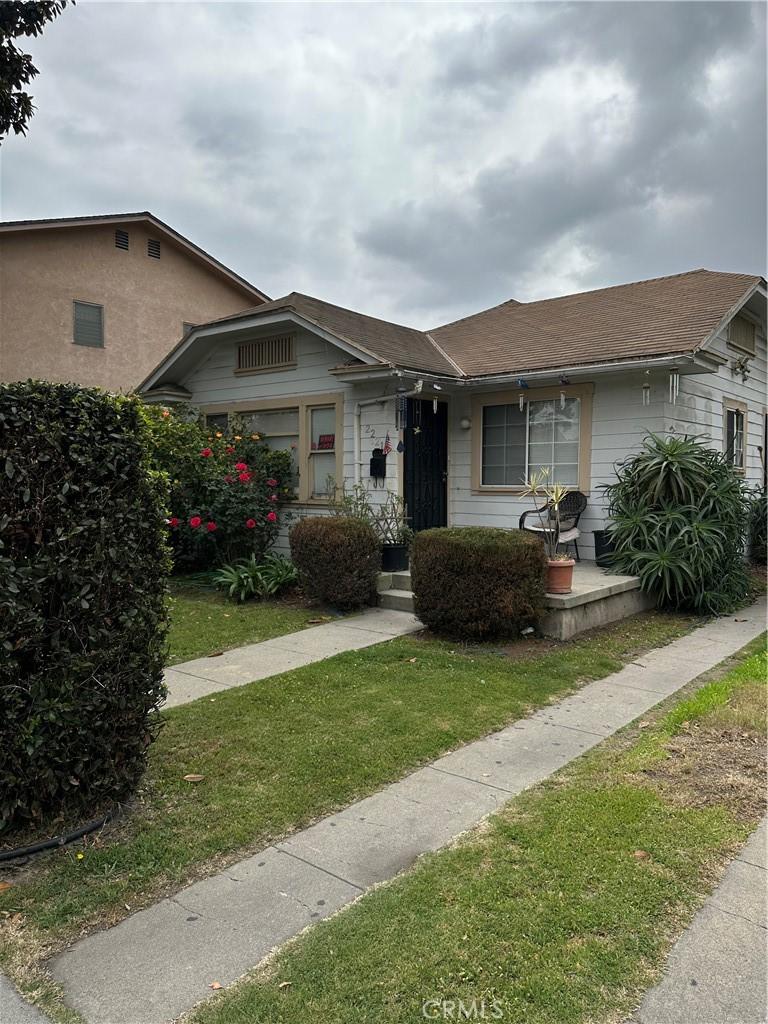 view of front of property featuring a porch, a shingled roof, and a front yard