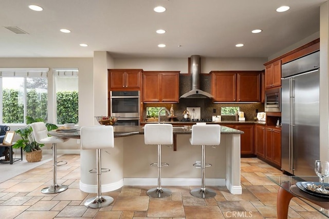 4505 Cresta Babia, San Clemente, CA 92673 - kitchen with built in appliances, wall chimney exhaust hood, recessed lighting, decorative backsplash, and a breakfast bar area