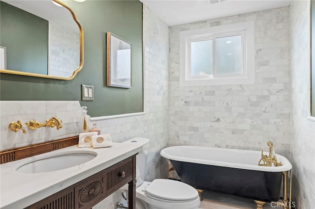 full bathroom with a freestanding bath, toilet, tile walls, visible vents, and vanity