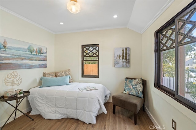 bedroom featuring lofted ceiling, wood finished floors, crown molding, and baseboards