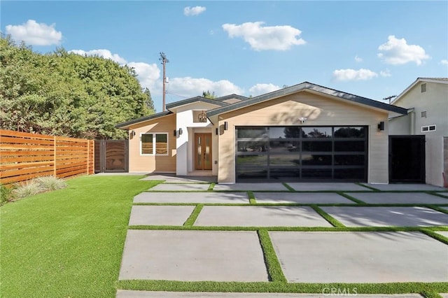 contemporary home featuring a garage, a front yard, concrete driveway, and fence