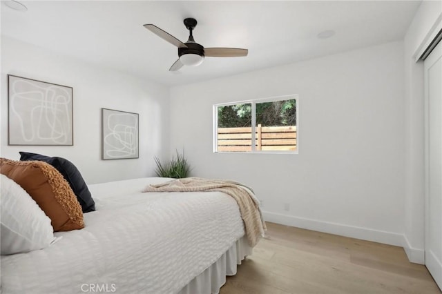 bedroom with light wood-style flooring, baseboards, a closet, and a ceiling fan