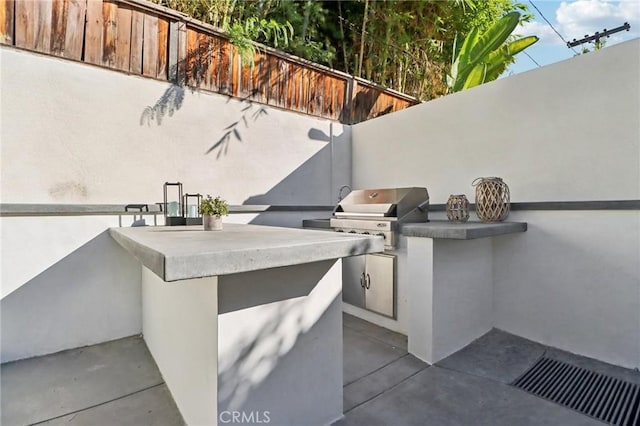 view of patio / terrace with fence, grilling area, visible vents, and exterior kitchen