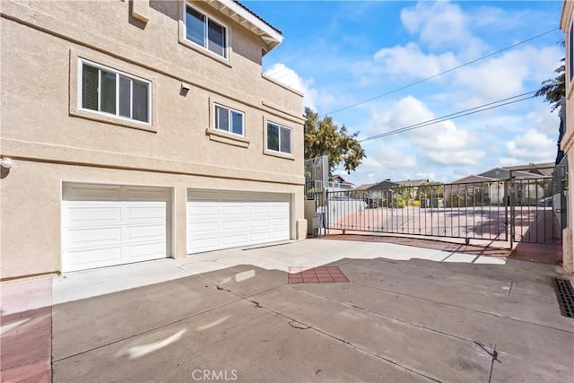 11415 216th St Unit 24, Lakewood, CA 90715 - view of side of property with a garage, concrete driveway, fence, and stucco siding