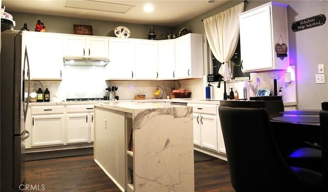 2653 Ashcroft Ave, Clovis, CA 93611 - kitchen with white cabinetry, backsplash, a kitchen island, and freestanding refrigerator