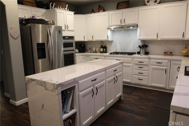 2653 Ashcroft Ave, Clovis, CA 93611 - kitchen with light stone countertops, under cabinet range hood, appliances with stainless steel finishes, white cabinetry, and dark wood-type flooring