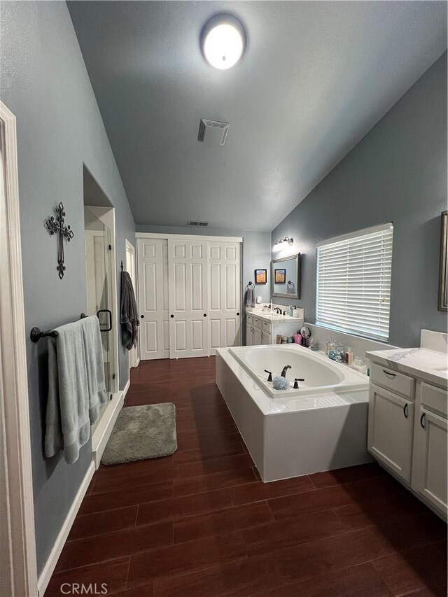 2653 Ashcroft Ave, Clovis, CA 93611 - bathroom with wood finished floors, vaulted ceiling, a bath, visible vents, and a stall shower