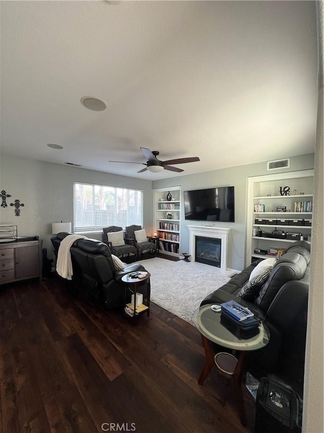 2653 Ashcroft Ave, Clovis, CA 93611 - living room featuring ceiling fan, built in features, a glass covered fireplace, visible vents, and wood finished floors